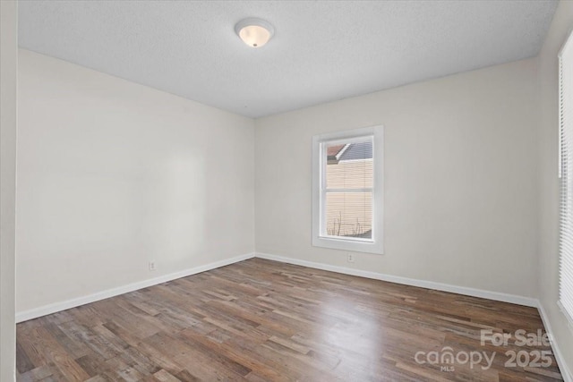 unfurnished room with dark hardwood / wood-style flooring and a textured ceiling