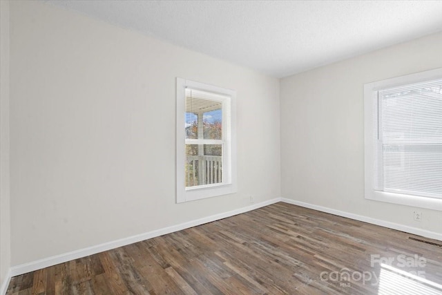 empty room featuring a textured ceiling and dark hardwood / wood-style flooring