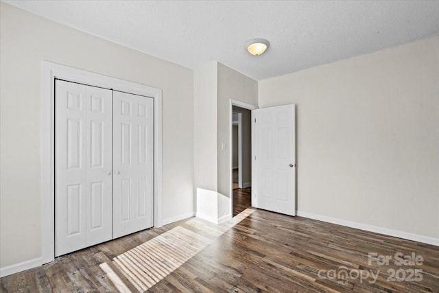 unfurnished bedroom featuring dark wood-type flooring, a textured ceiling, and a closet