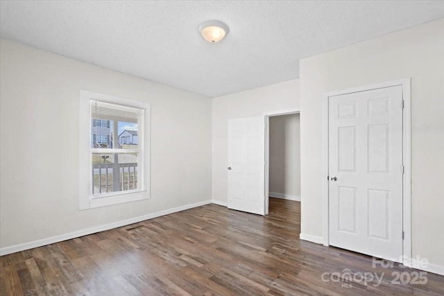 unfurnished bedroom with dark hardwood / wood-style flooring and a textured ceiling