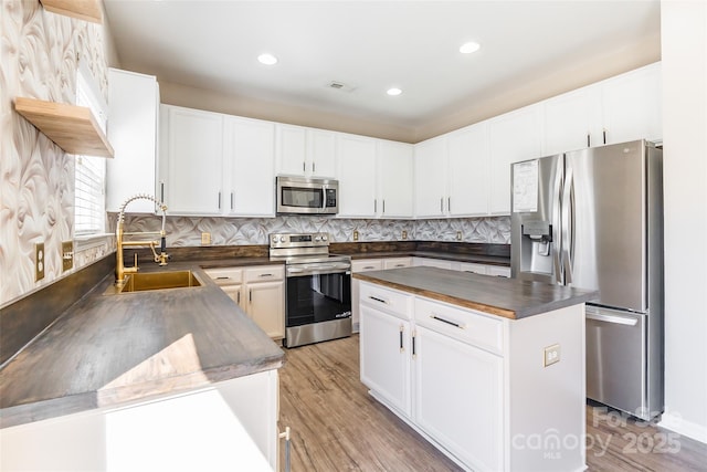 kitchen featuring decorative backsplash, white cabinetry, stainless steel appliances, and a sink