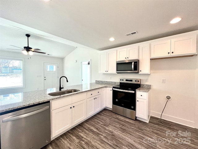 kitchen with light stone counters, a sink, visible vents, white cabinetry, and appliances with stainless steel finishes