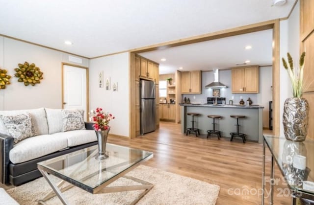 living room with light hardwood / wood-style floors and crown molding