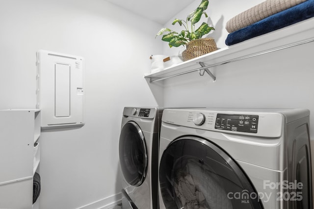 clothes washing area with laundry area, washing machine and dryer, electric panel, and baseboards