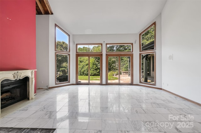 unfurnished living room with a high end fireplace and a towering ceiling