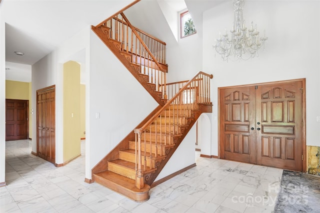 stairway featuring a towering ceiling and a chandelier