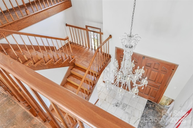 staircase with a notable chandelier, parquet flooring, and a high ceiling