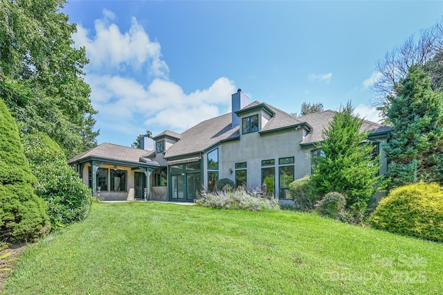 rear view of property featuring a sunroom and a lawn