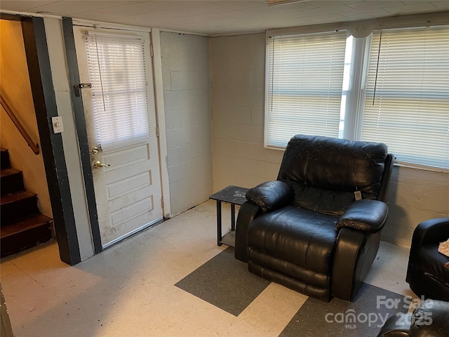 sitting room featuring concrete block wall and stairway