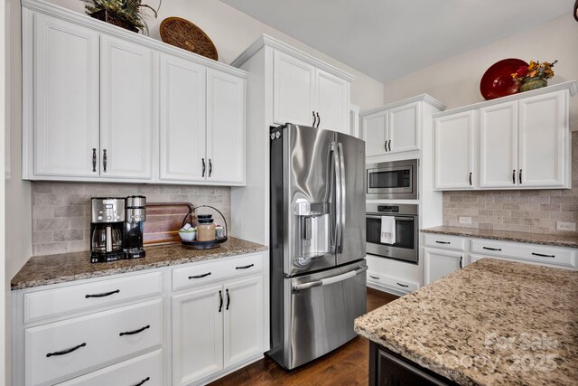 kitchen featuring light stone counters, stainless steel appliances, tasteful backsplash, dark wood-type flooring, and white cabinetry