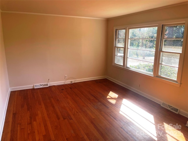 empty room with crown molding and dark wood-type flooring