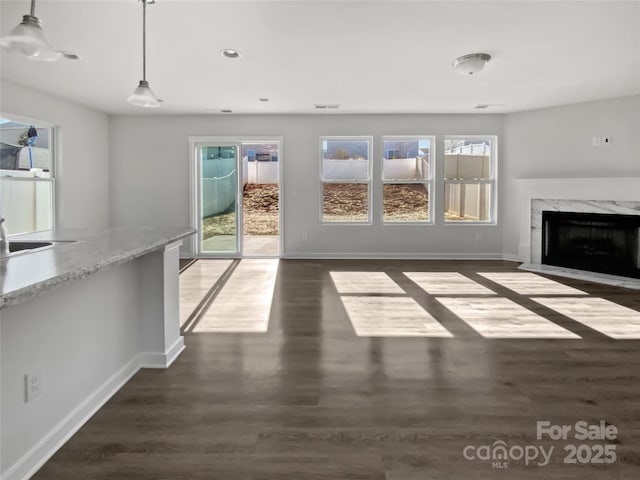 unfurnished living room with a healthy amount of sunlight, dark hardwood / wood-style flooring, and a fireplace