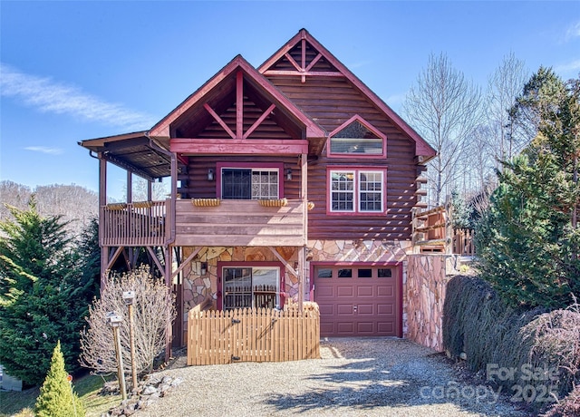 log home with gravel driveway, stone siding, an attached garage, and log siding