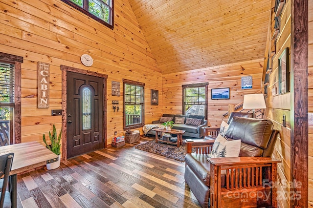 entrance foyer featuring wood walls, a towering ceiling, and hardwood / wood-style floors