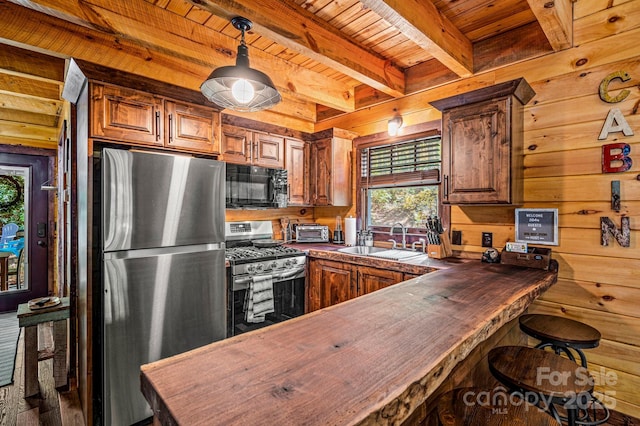 kitchen featuring butcher block counters, appliances with stainless steel finishes, a sink, wood walls, and wooden ceiling