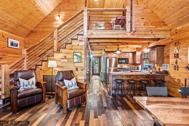 living area with dark wood-style floors, wood ceiling, wooden walls, and high vaulted ceiling