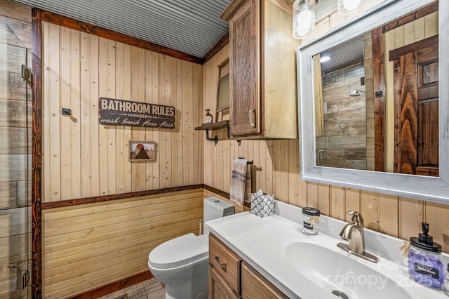 bathroom featuring toilet, wooden walls, and vanity