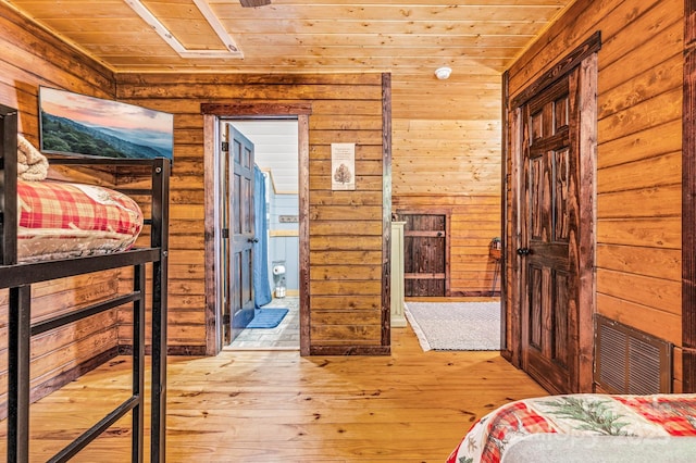 unfurnished bedroom featuring visible vents, wood ceiling, connected bathroom, wood walls, and hardwood / wood-style floors