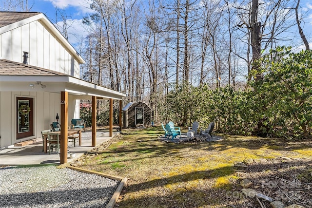 view of yard with a shed, a fire pit, an outbuilding, and a patio