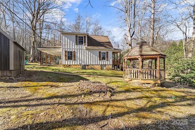 back of house with driveway, a shingled roof, a gazebo, a yard, and a carport