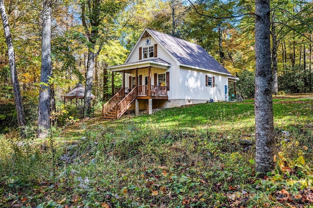 view of front of house featuring a porch, a shingled roof, crawl space, a front lawn, and stairs