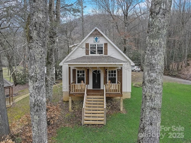 view of front of house featuring a porch, stairway, roof with shingles, a front lawn, and board and batten siding