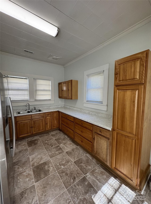 kitchen with visible vents, brown cabinetry, stainless steel fridge with ice dispenser, light countertops, and a sink