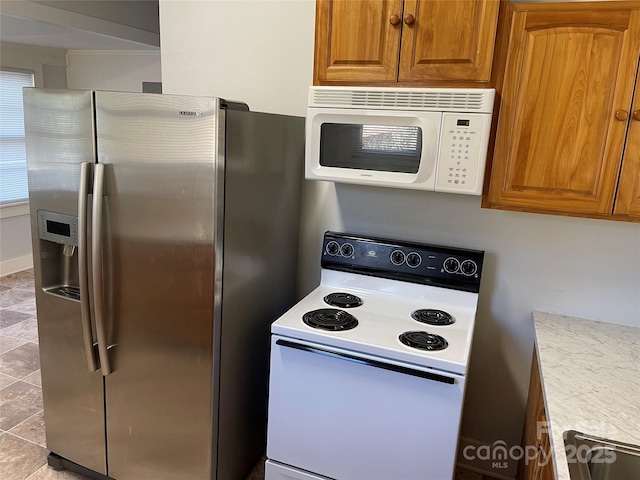 kitchen featuring white appliances, brown cabinets, and light countertops