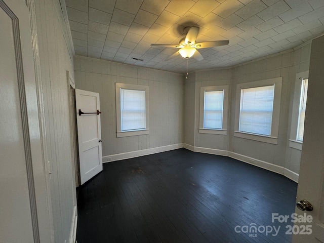 spare room with visible vents, dark wood-type flooring, a ceiling fan, and baseboards