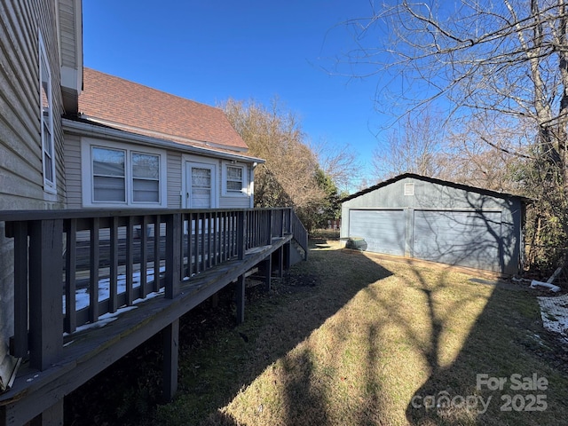 view of side of home featuring a shingled roof, a wooden deck, a lawn, and an outdoor structure