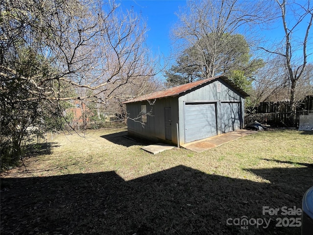 view of yard featuring an outbuilding, a detached garage, and fence