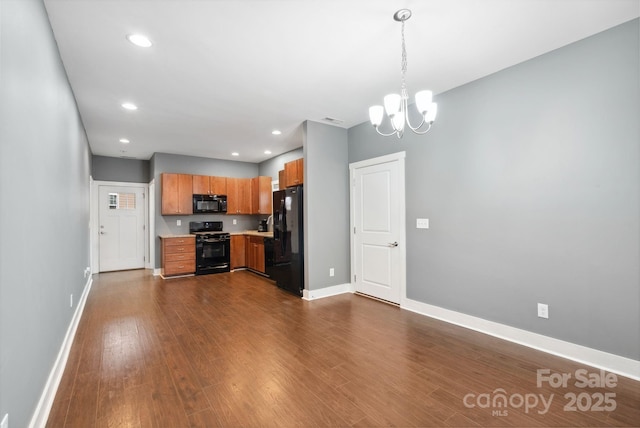 kitchen featuring pendant lighting, dark wood-type flooring, black appliances, and a chandelier