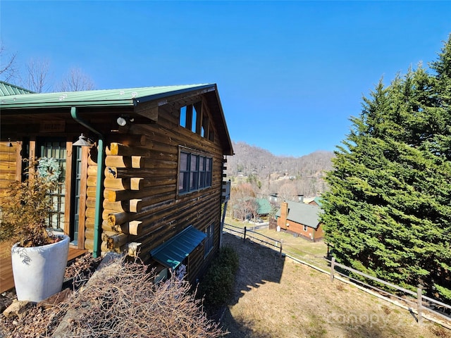 view of side of home with log exterior and fence