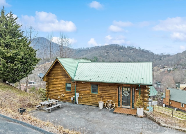 exterior space with a mountain view, log exterior, and metal roof