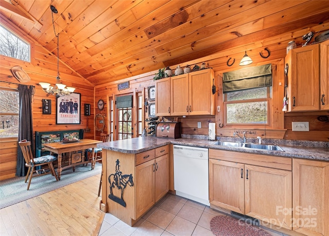 kitchen featuring a sink, a peninsula, wood walls, white dishwasher, and lofted ceiling