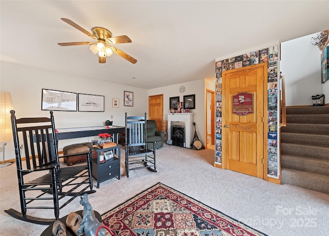 carpeted home office with ceiling fan and a fireplace