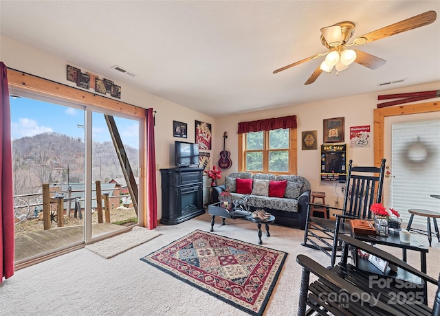 carpeted living area featuring visible vents, a mountain view, and a ceiling fan