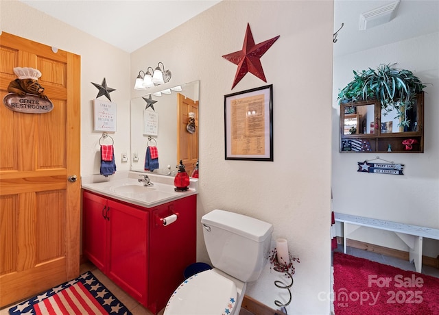 bathroom with vanity, toilet, and visible vents