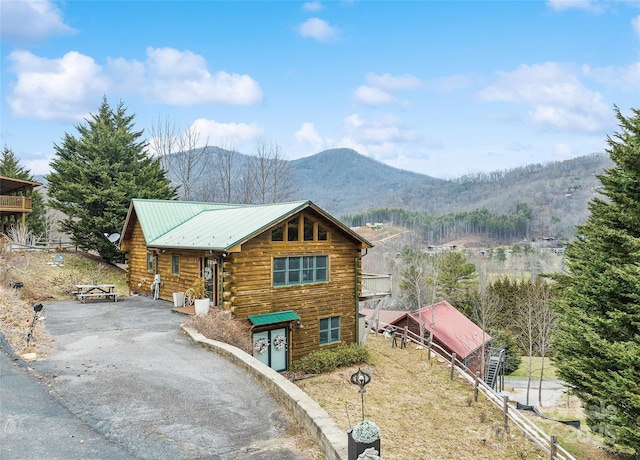 cabin with aphalt driveway, log siding, a mountain view, and metal roof