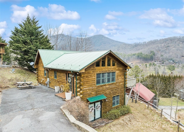 log cabin featuring log siding, a mountain view, metal roof, and aphalt driveway