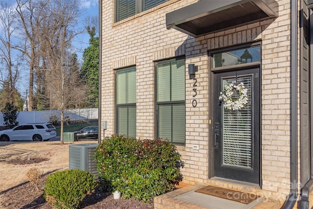 entrance to property with central air condition unit and brick siding