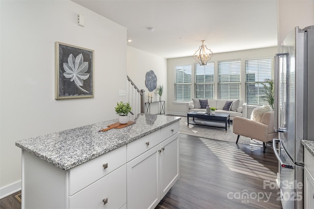 kitchen with dark wood-type flooring, white cabinets, open floor plan, freestanding refrigerator, and light stone countertops