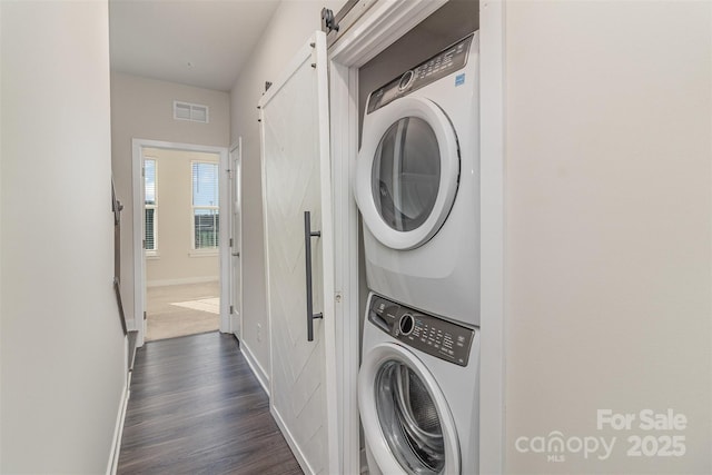 laundry area featuring laundry area, dark wood-type flooring, visible vents, baseboards, and stacked washing maching and dryer