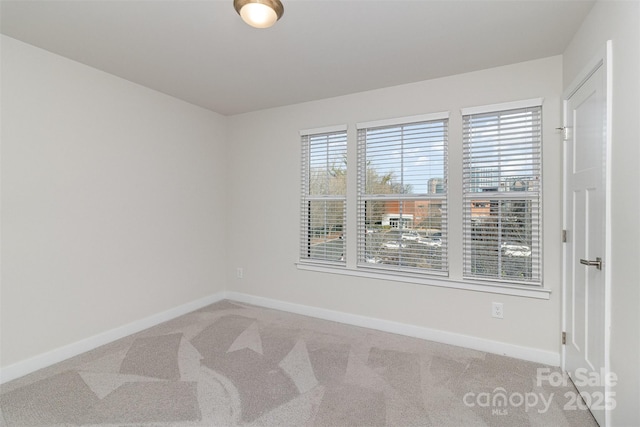 spare room featuring carpet floors and baseboards