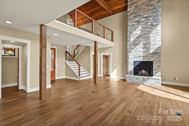 unfurnished living room with a fireplace, stairway, baseboards, and wood finished floors