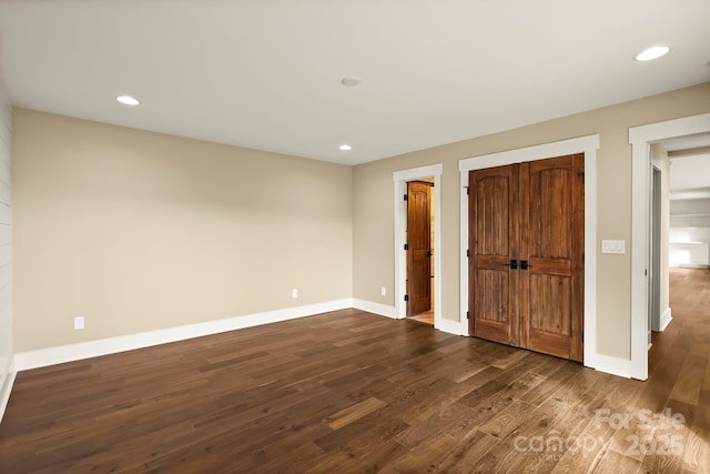 unfurnished bedroom featuring dark wood-type flooring, a closet, recessed lighting, and baseboards