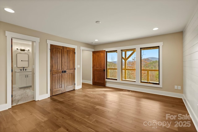 unfurnished bedroom with baseboards, wood finished floors, and recessed lighting