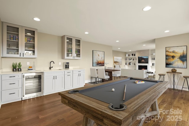 game room featuring wine cooler, dark wood finished floors, pool table, a sink, and a warm lit fireplace