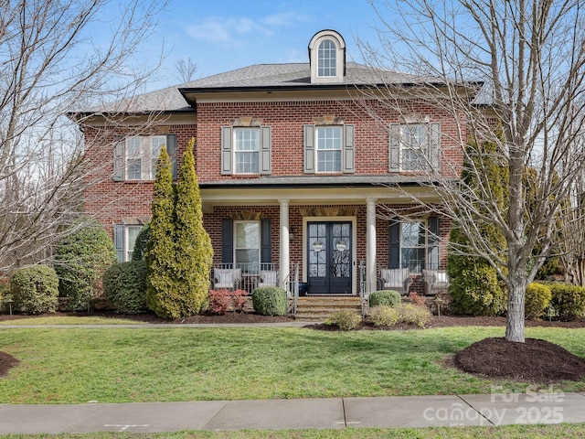 view of front of home featuring covered porch, brick siding, and a front lawn