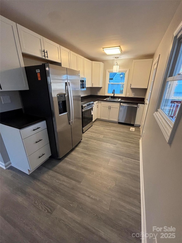 kitchen featuring stainless steel appliances, a wealth of natural light, light hardwood / wood-style floors, white cabinets, and sink